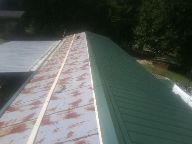 Old rusted panels beside newly installed green metal roofing — Wind Damage Roof Repair by Roofing Brothers in Raleigh